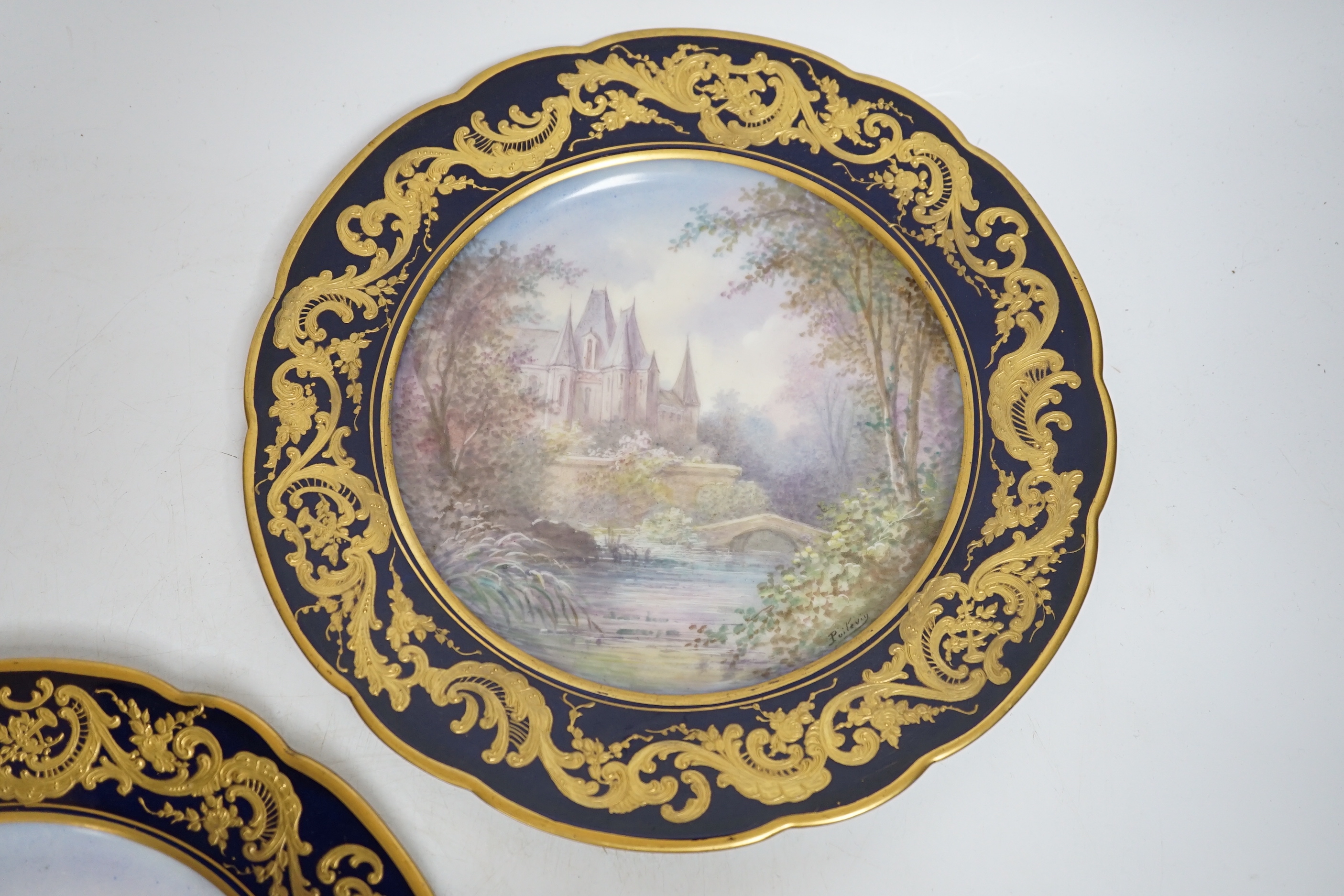 A pair of Sevres style blue cabinet plates, each decorated with a chateau, 24.5cm diameter